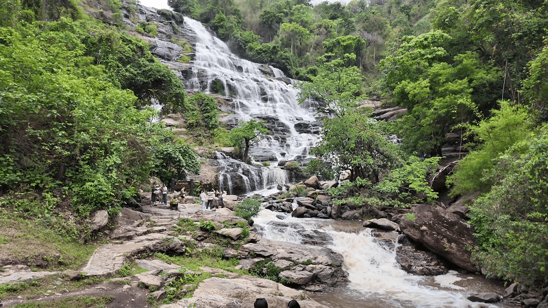 Mae Ya Waterfall - One of Chiang Mais Most Beautiful Waterfalls Mae Ya Waterfall flowing across a wide rocky cliff with green vegetation